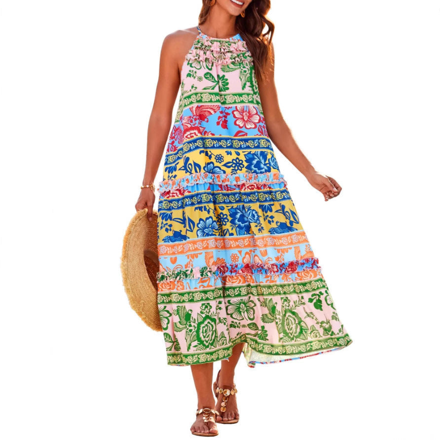 Colorful boho dress with floral patterns, worn by a person holding a straw hat, against a white studio background.