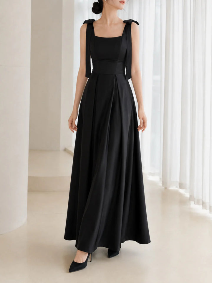 Elegant black dress with bow straps in a bright room with white curtains.