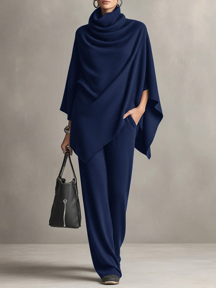Navy blue two-piece set with elegant draped top and wide-leg pants in studio setting, accessorized with black handbag.