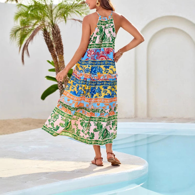 Person wearing a colorful boho dress with floral patterns, walking by a pool with palm trees and white walls.