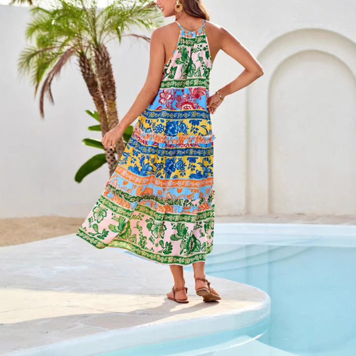 Person wearing a colorful boho dress with floral patterns, walking by a pool with palm trees and white walls.