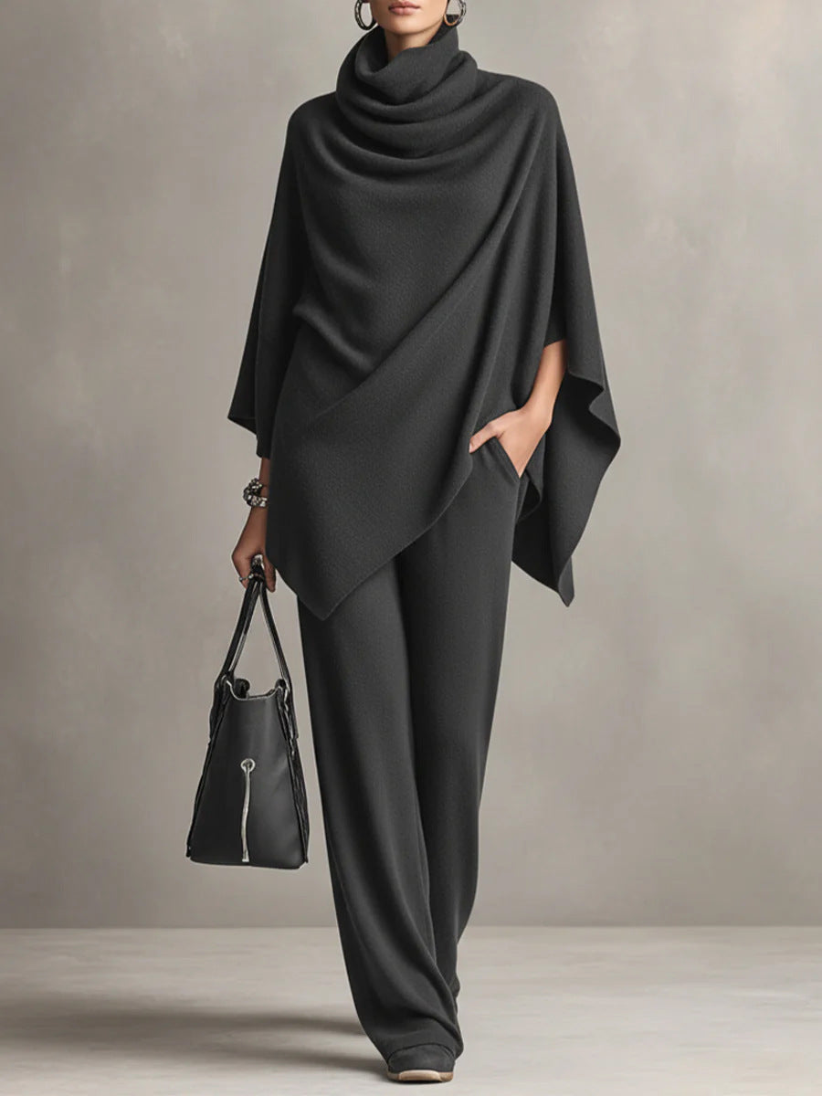 Black two-piece set with elegant draped top and wide-leg pants in studio setting, accessorized with a black handbag.