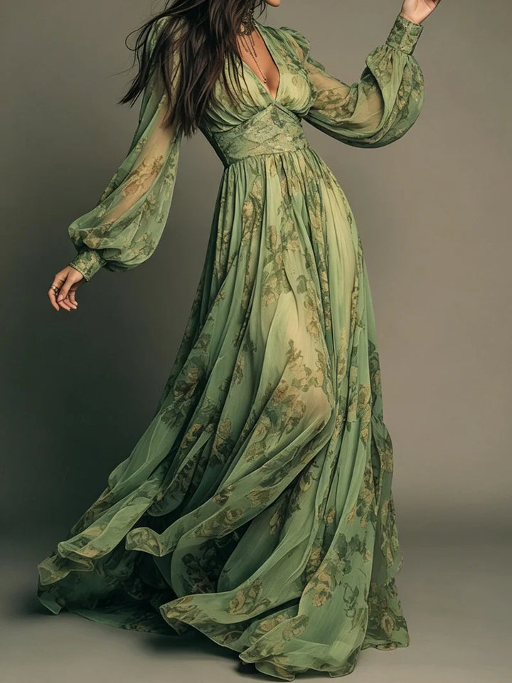 Flowing green maxi dress with floral patterns, featuring long sheer sleeves, modeled in a studio setting.
