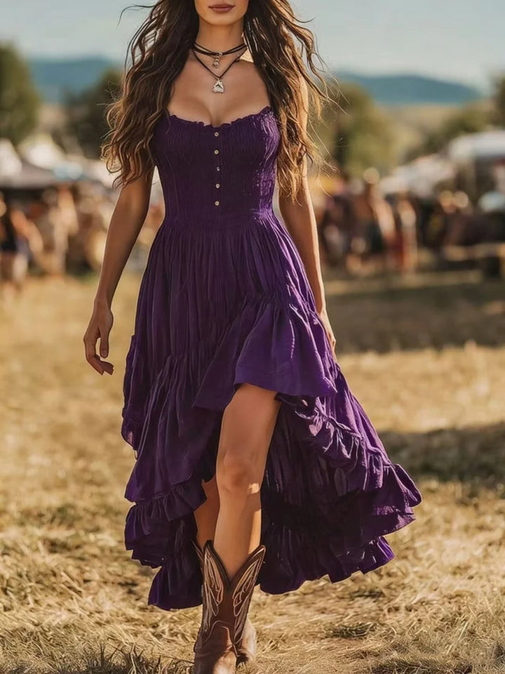 Woman in a purple maxi dress with tiered skirt and cowboy boots at an outdoor festival.
