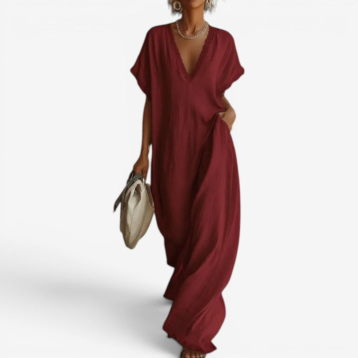 Elegant red maxi dress with lace-trimmed V-neckline, carried by a woman with a beige bag, set against a plain background.