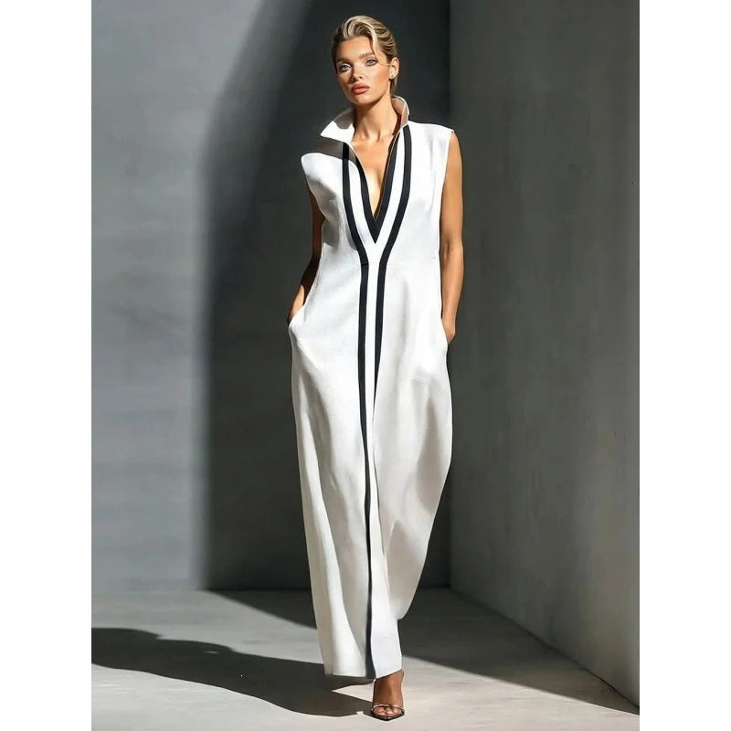Chic white sleeveless maxi dress with black stripes in a minimalist indoor setting.