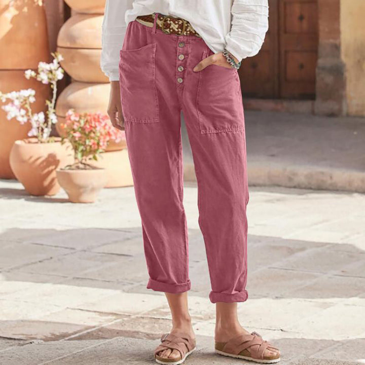 Pink casual pants with button front and rolled cuffs, worn outdoors with white top and sandals.