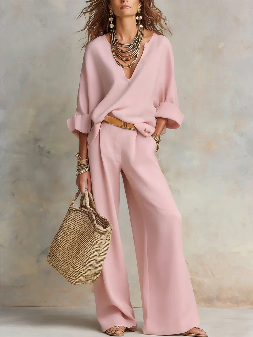 Pink two-piece set with a relaxed fit, paired with statement jewelry and a woven bag against a neutral studio background.