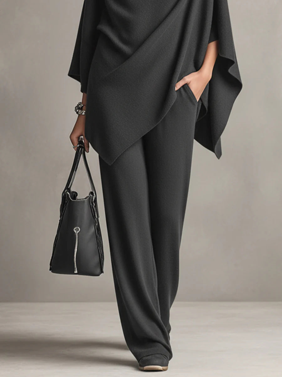 Black wide-leg pants and draped top detail with black handbag in studio setting.