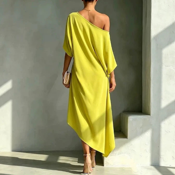 Back view of the elegant asymmetrical yellow robe, showcasing the drape and design in a minimalist studio environment.
