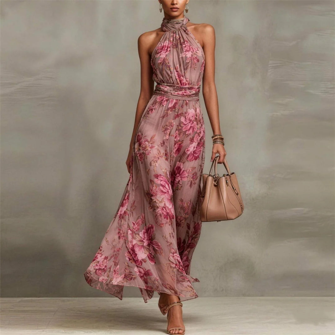 Pink floral halter-neck maxi dress in studio setting with beige handbag.
