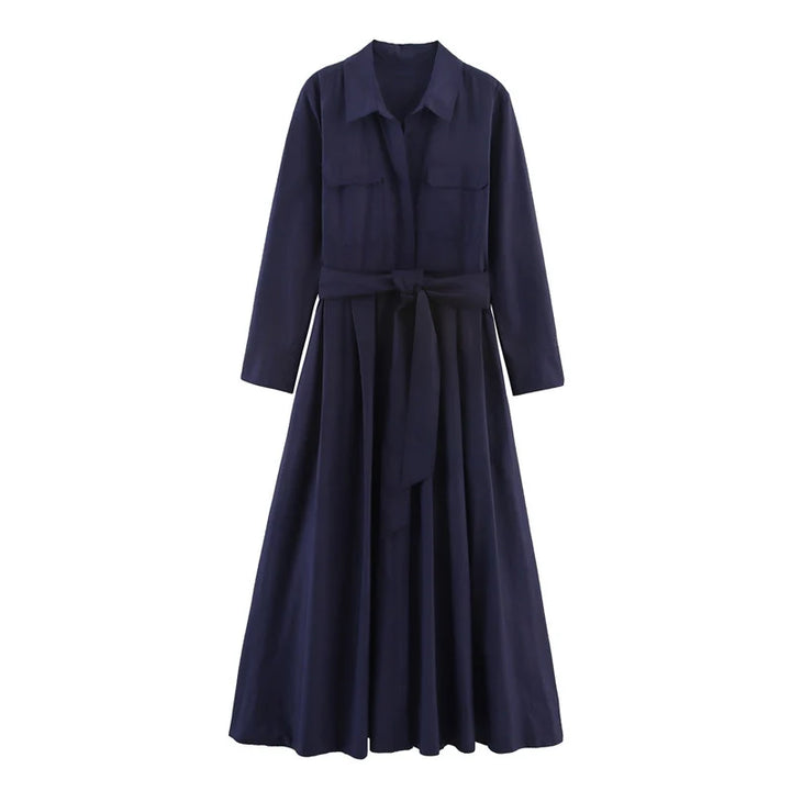 Studio image of an elegant navy loose dress with long sleeves and a belted waist on a white background.