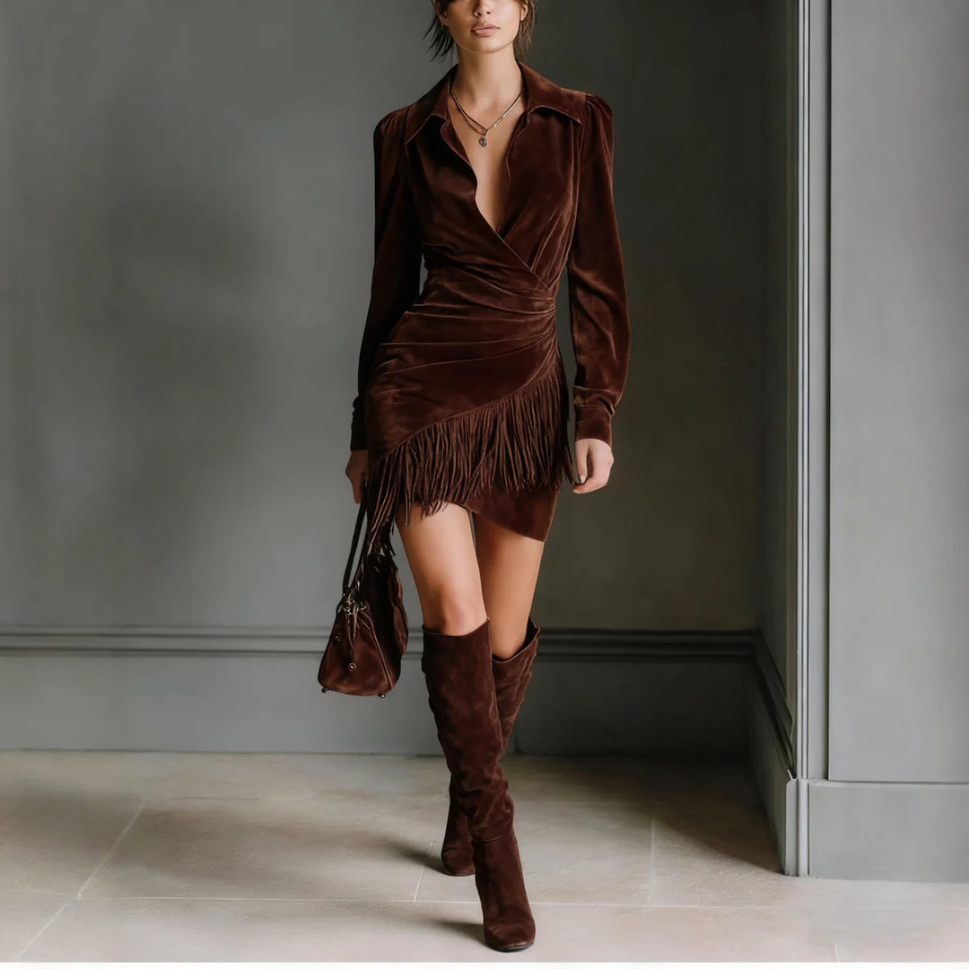 Chic woman wearing a brown mini dress with fringe detail and knee-high boots, in a sophisticated indoor space.