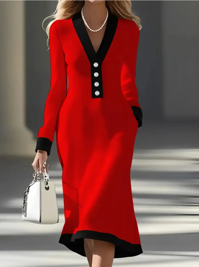 Red long-sleeve dress with black trim and buttons, accessorized with a pearl necklace and white handbag, in a city setting.