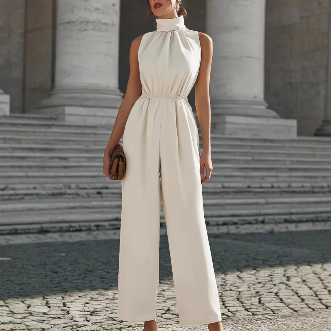 Elegant cream-colored jumpsuit with high collar and cinched waist, showcased in a classic architectural setting with stone steps.