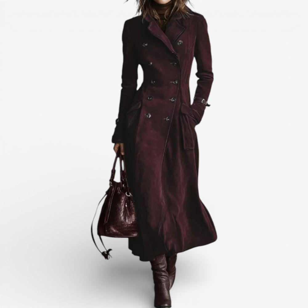 Woman in a long burgundy suede coat with double-breasted buttons, brown boots, holding a matching bag on a white background.