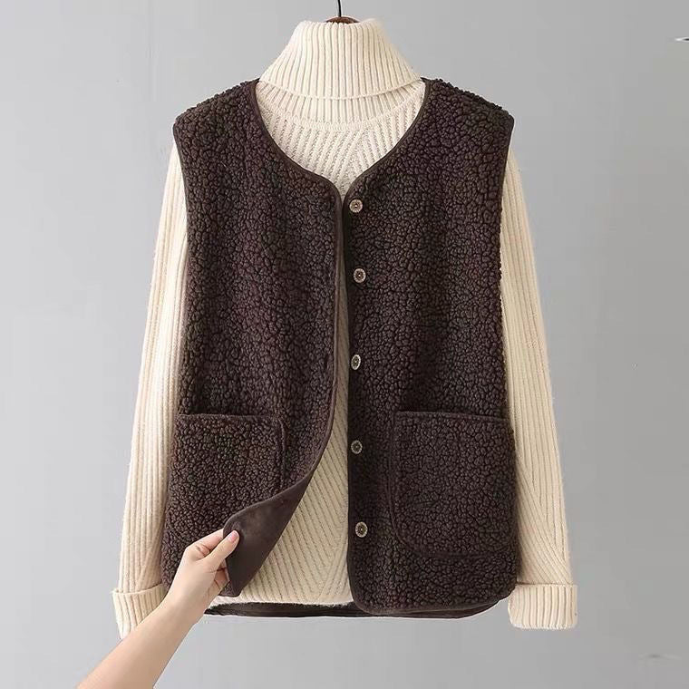 Cozy dark brown sleeveless cardigan with pockets over a cream ribbed turtleneck on a hanger in a plain gray studio.