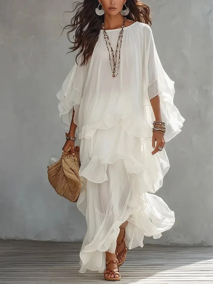 Chic, layered white dress featuring soft ruffles and stylish jewelry, complemented by a woven handbag in a studio setting.