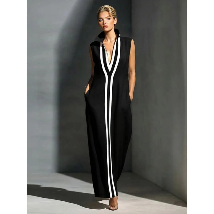 Stylish black sleeveless maxi dress with white stripes in a minimalist indoor setting.
