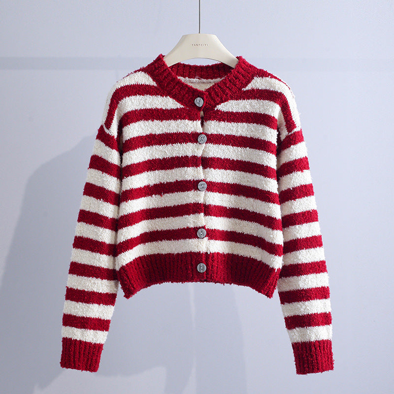 Red and white striped cardigan with buttons, hanging in a studio with a light gray background.