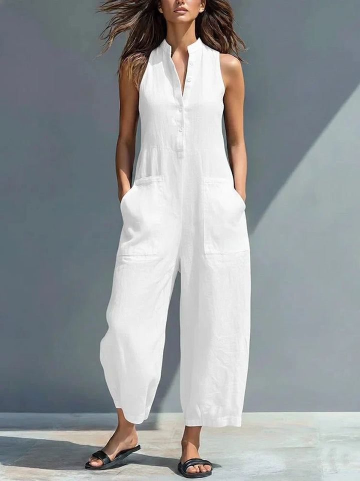 Woman wearing a white sleeveless jumpsuit with pockets, outdoors in natural light.
