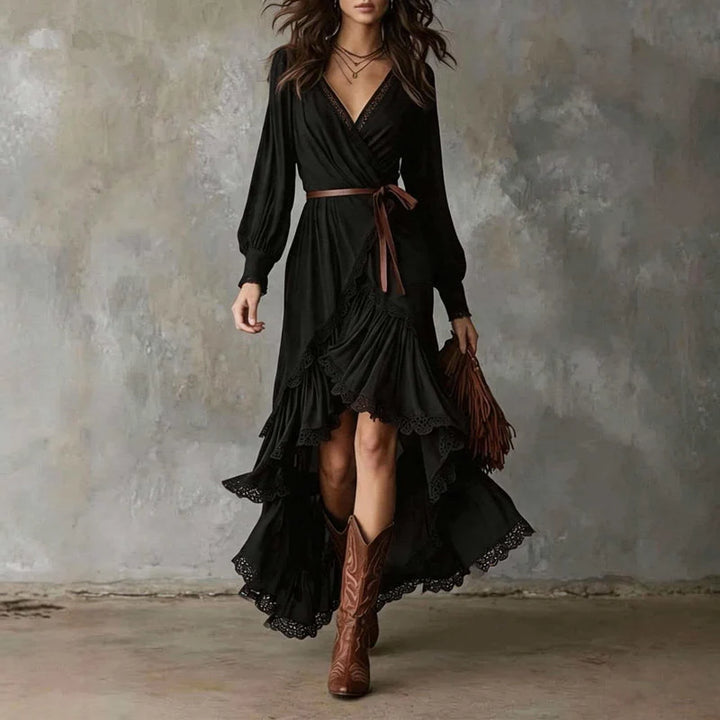 Black wrap midi dress with ruffled hem, worn with brown boots, against a textured gray wall.