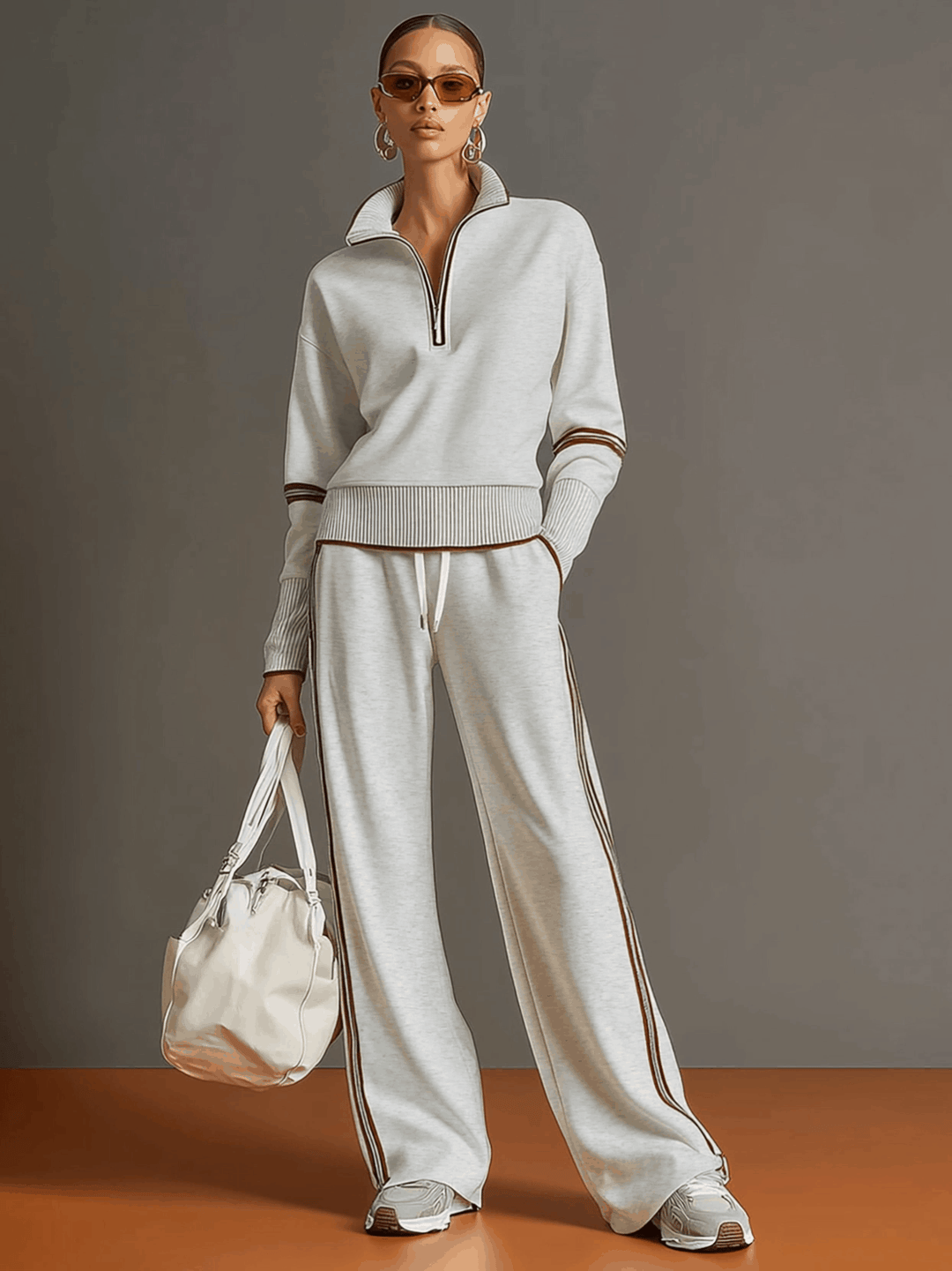 Effortless matching lounge set in light gray with contrast stripes, styled with white sneakers and a bag in a studio setting.