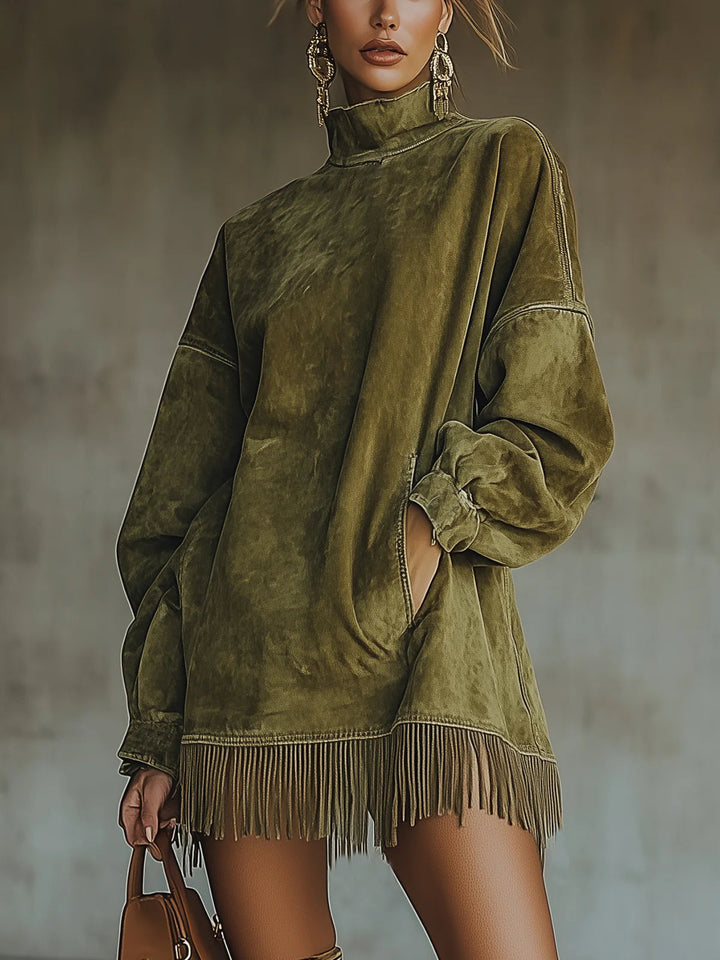 Green suede fringe dress with high neck and long sleeves, modeled indoors against a blurred background, paired with a brown handbag.