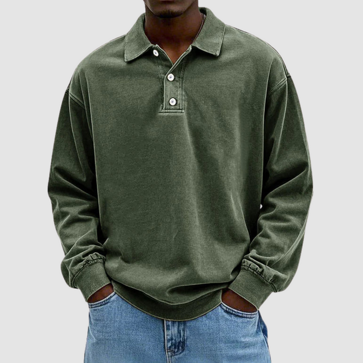 Dark green vintage long sleeve polo shirt worn by model, hands in pockets, paired with light jeans, studio backdrop.