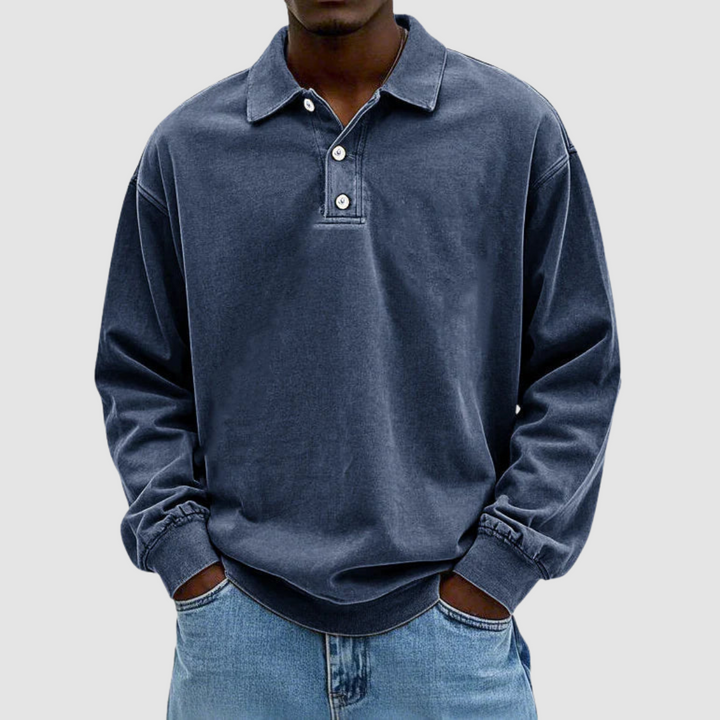 Navy vintage long sleeve polo shirt worn by model, hands in pockets, with light jeans, simple background.