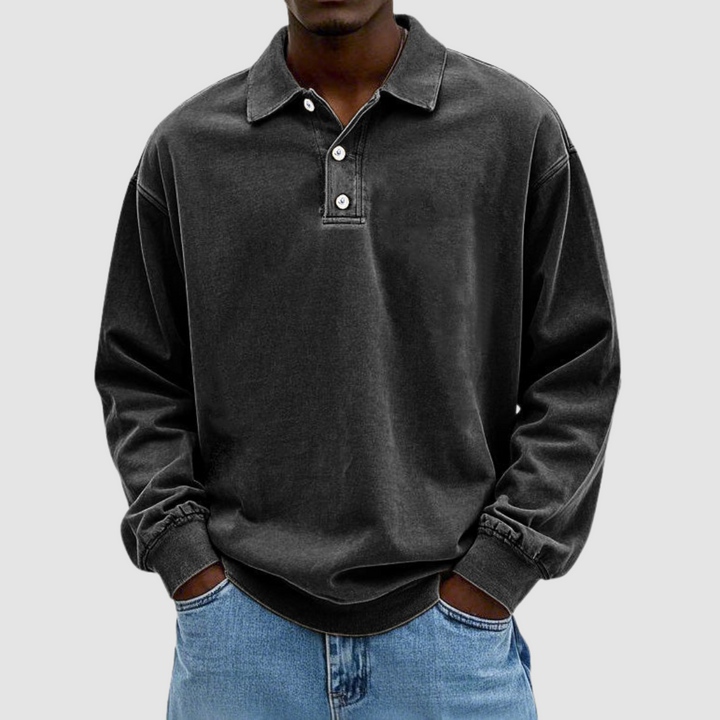 Black vintage long sleeve polo shirt worn by model, hands in pockets, paired with light jeans, plain backdrop.