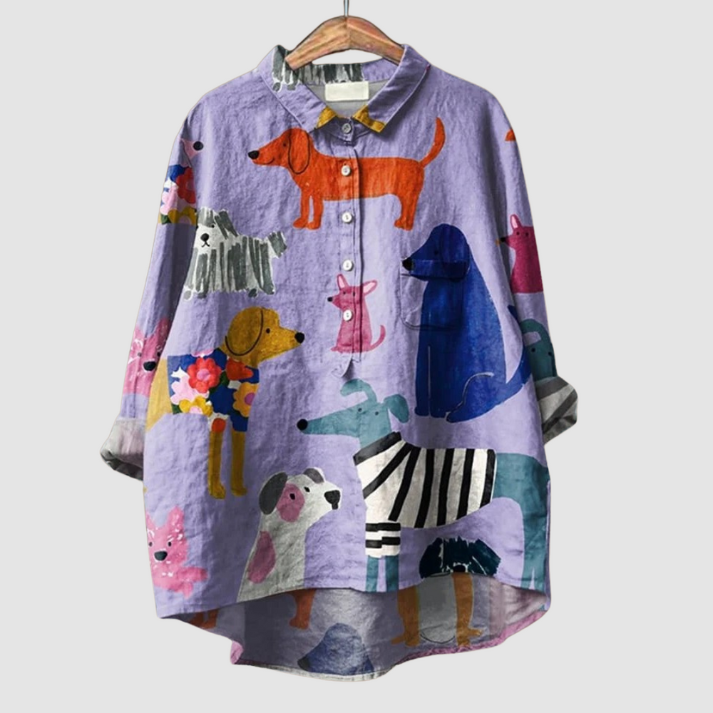 Loose purple shirt with vibrant dog prints displayed on a hanger, set against a plain background.