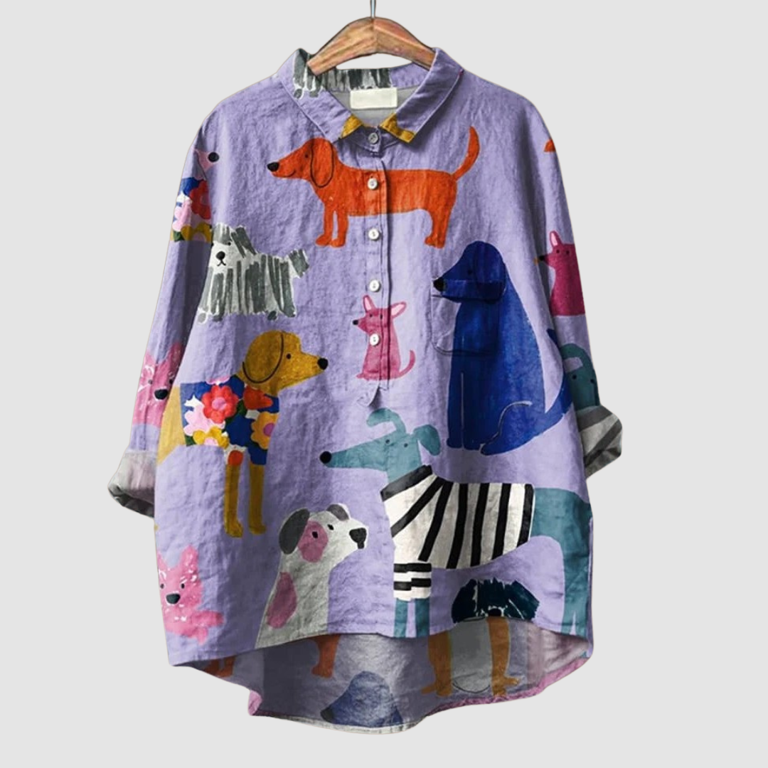 Loose purple shirt with vibrant dog prints displayed on a hanger, set against a plain background.