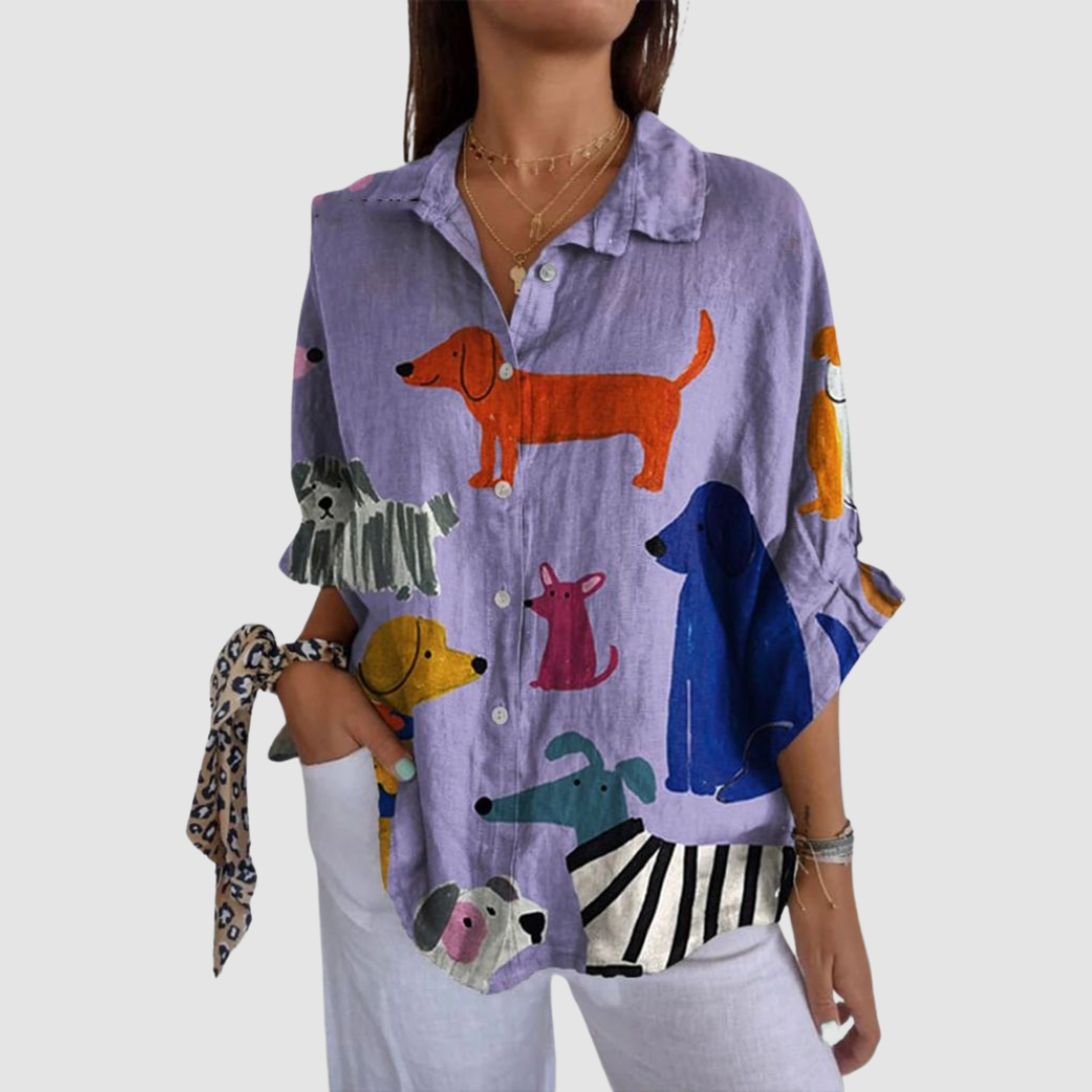 Woman wearing loose purple shirt with colorful dog prints, against a plain background.