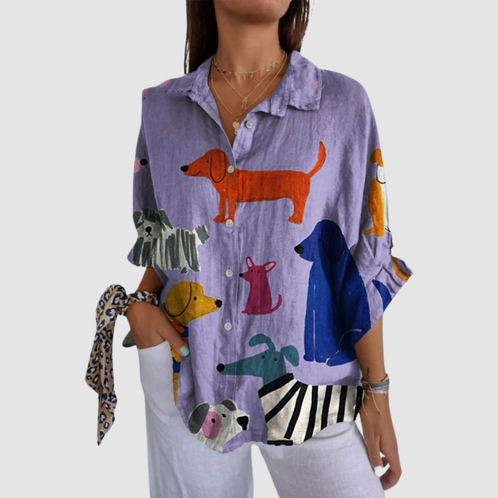 Woman wearing loose purple shirt with colorful dog prints, against a plain background.
