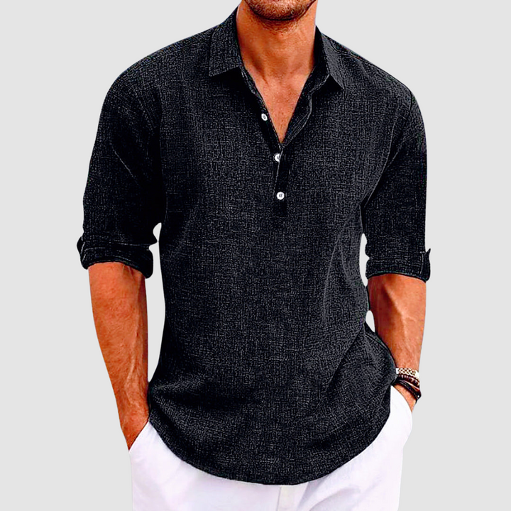 Black collared shirt with rolled up sleeves and buttons, worn by a person with hands in white pants pockets.