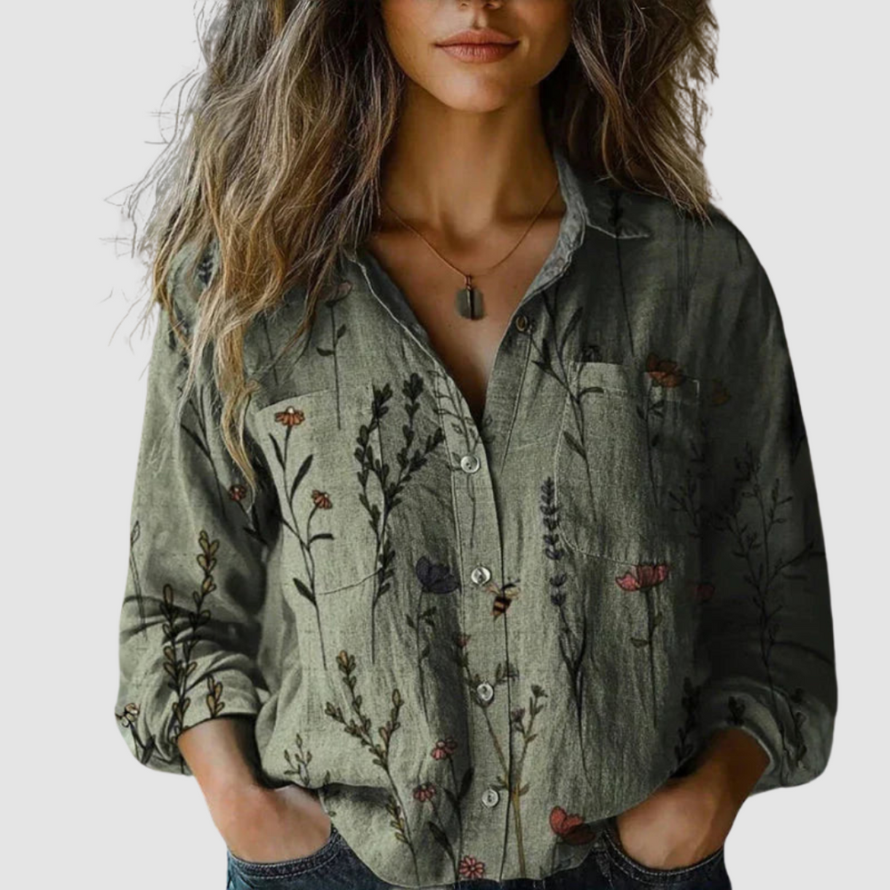 Model in a green blouse featuring floral prints and a button-down design, posed on a neutral backdrop.