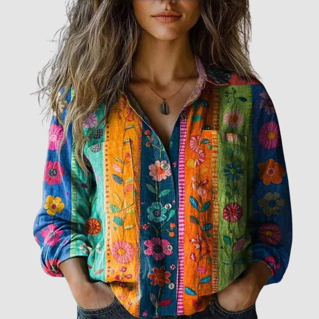 Colorful blouse with vertical floral stripes, buttoned down, modeled by a woman on a plain background.
