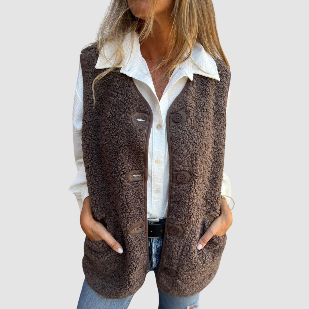 Person wearing a brown buttoned vest with a textured finish over a white shirt in a studio setting.