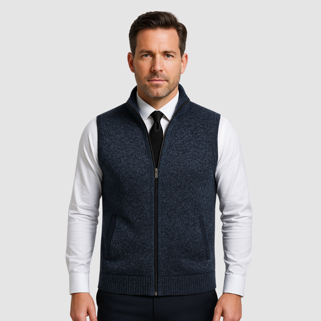 Man wearing dark fleece gilet over white shirt and black tie in studio.