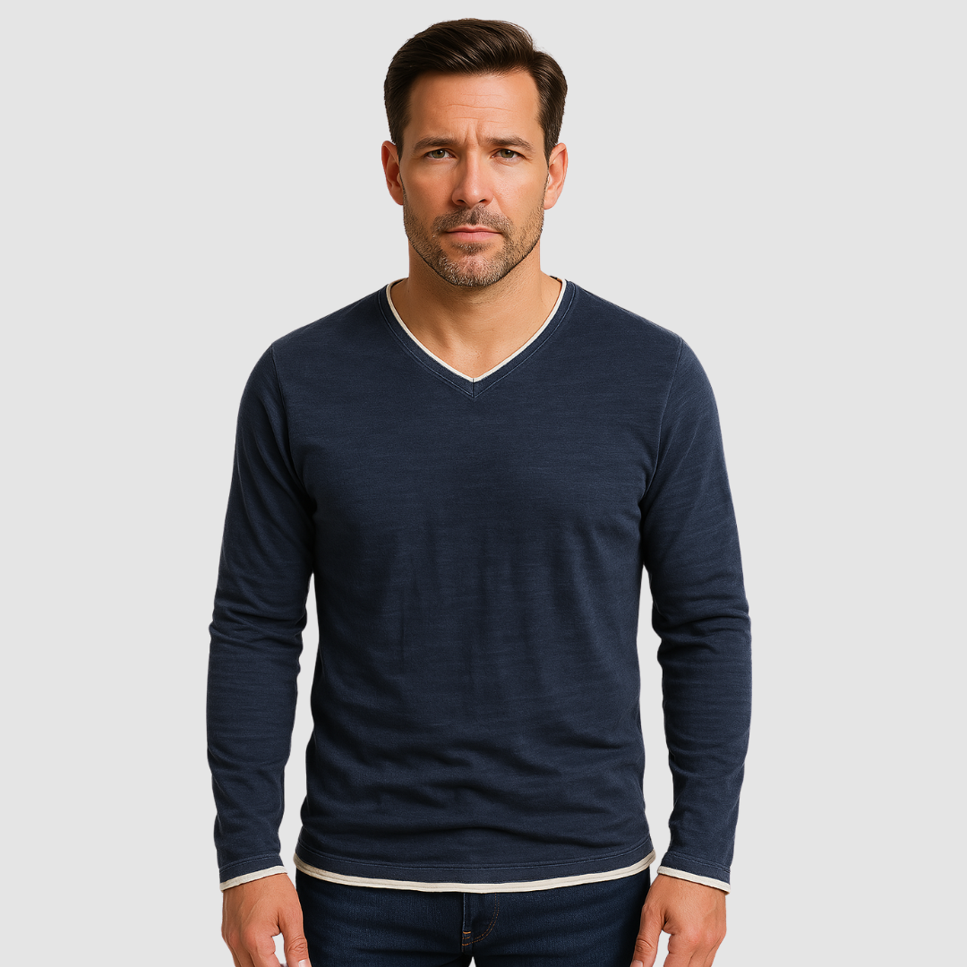 Man wearing a navy long sleeve shirt with white trim, standing against a light gray background.
