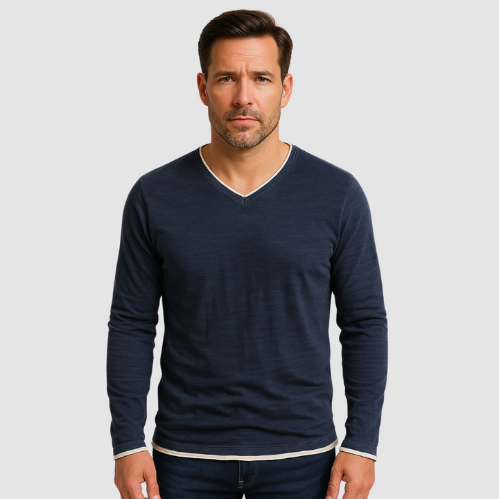 Man wearing a navy long sleeve shirt with white trim, standing against a light gray background.