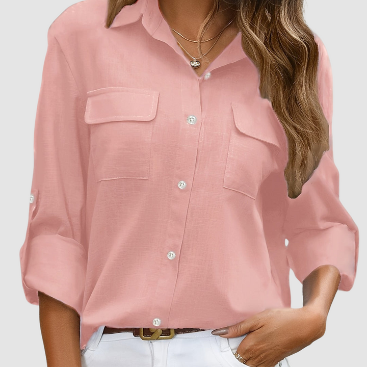 Pink pocket blouse with rolled sleeves, two front pockets, worn with necklaces, studio setting.