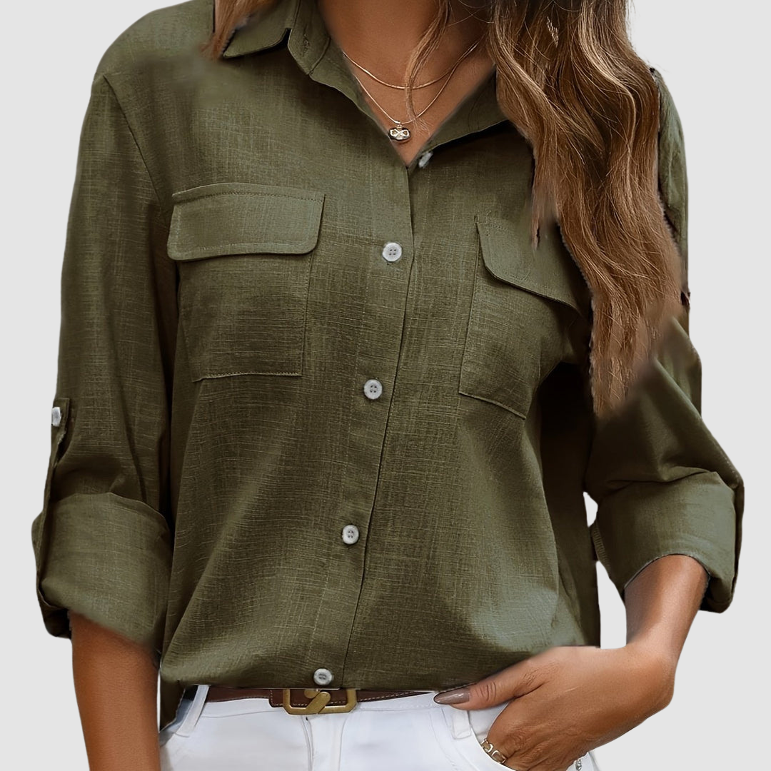 Olive pocket blouse with rolled sleeves, two front pockets, worn with necklaces, studio setting.