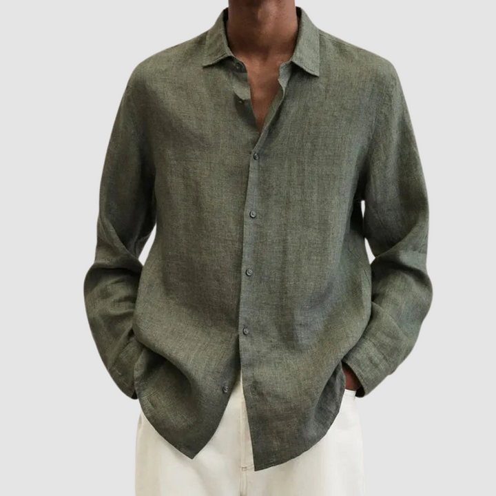 Model wearing an olive lightweight shirt with hands in pockets, against a light gray background.
