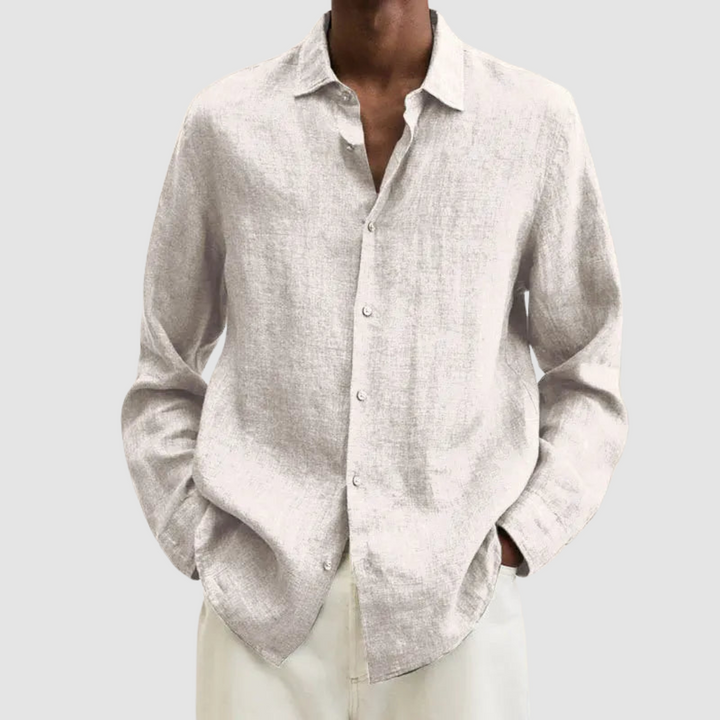 Model wearing a light beige lightweight shirt with hands in pockets, against a light gray background.