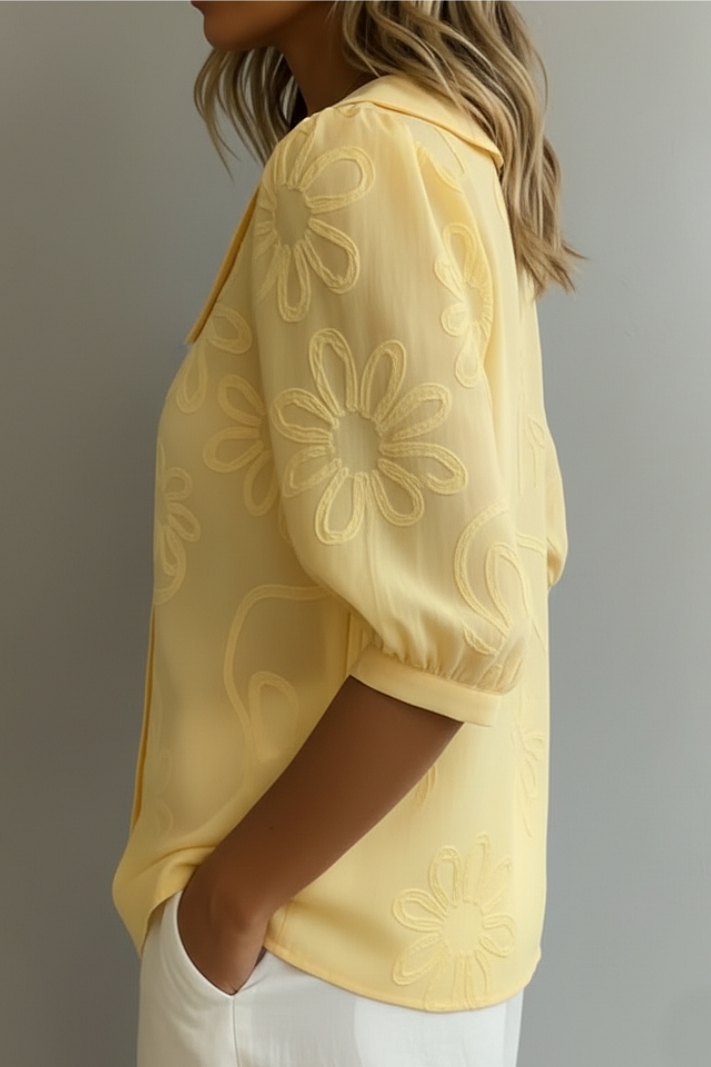 Side view of yellow floral blouse worn by a woman, neutral background.