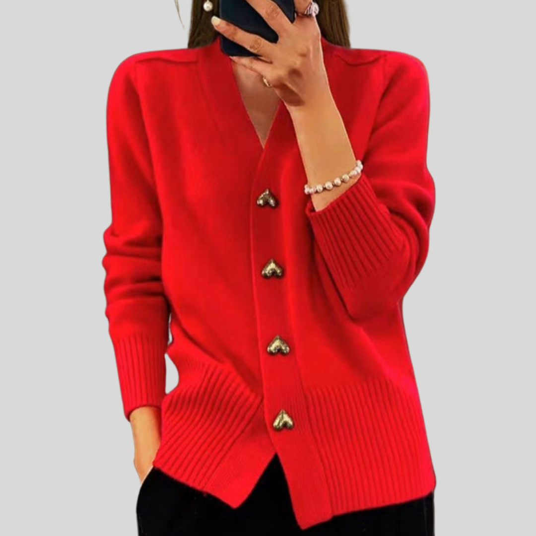 Bright red cardigan showcasing heart-shaped buttons, paired with black pants against a gray background.