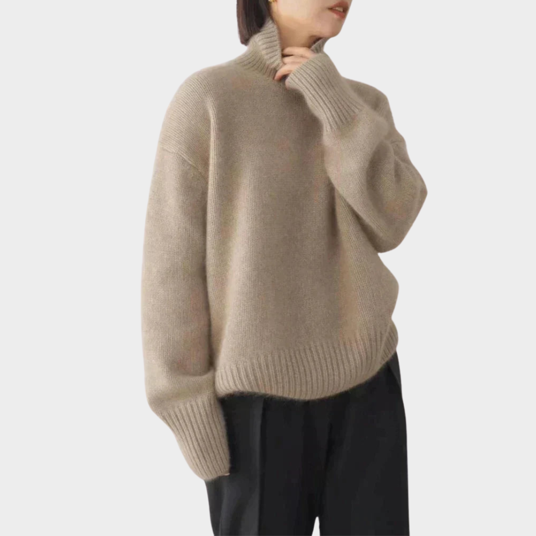 Taupe soft turtleneck jumper with ribbed details, styled with black pants, worn by a model, studio background.