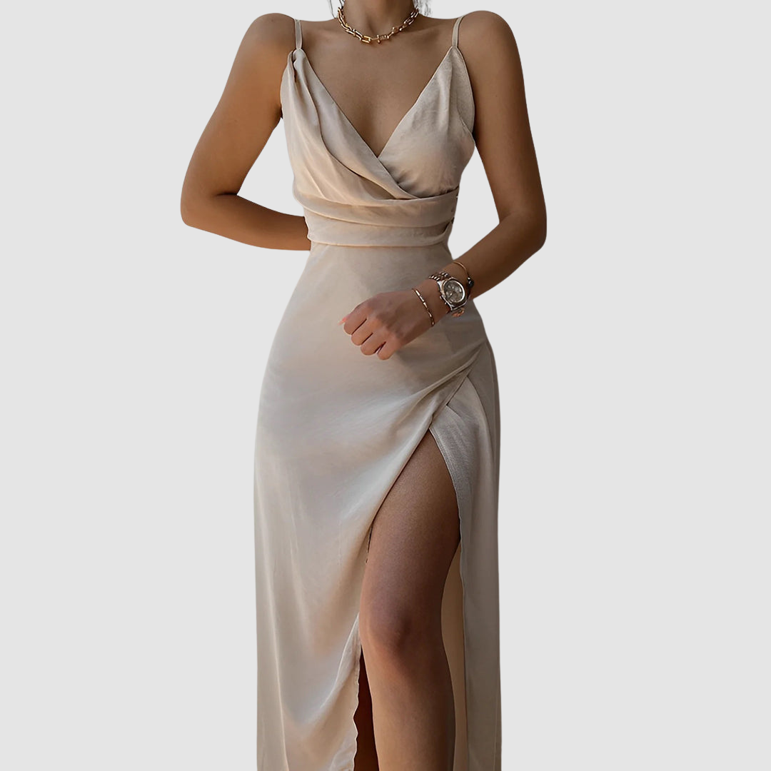 Elegant light beige dress with draped bodice and thigh-high slit, worn in a studio setting.